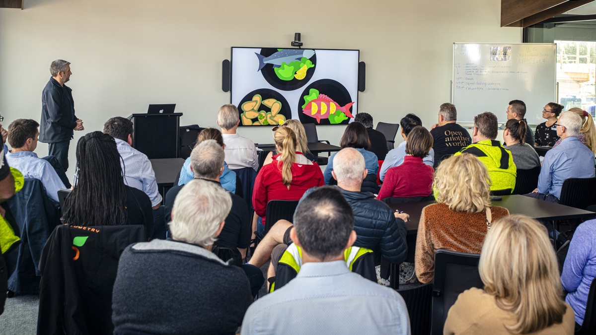 An audience of businesspeople listen to a presenter