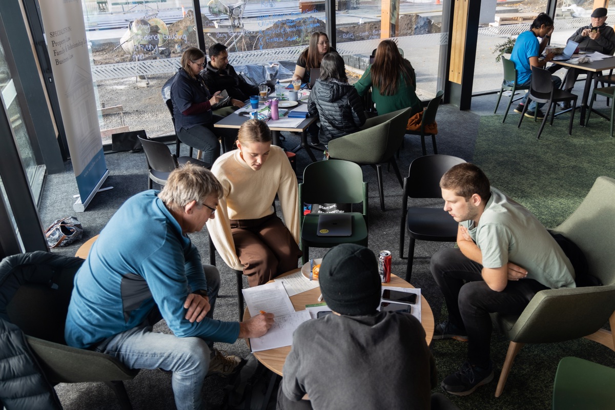 A small group have a discussion around a coffee table, taking notes