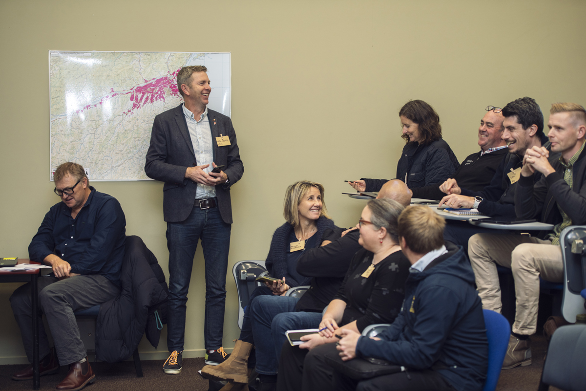 A business audience in an auditorium share a laugh with the presenter